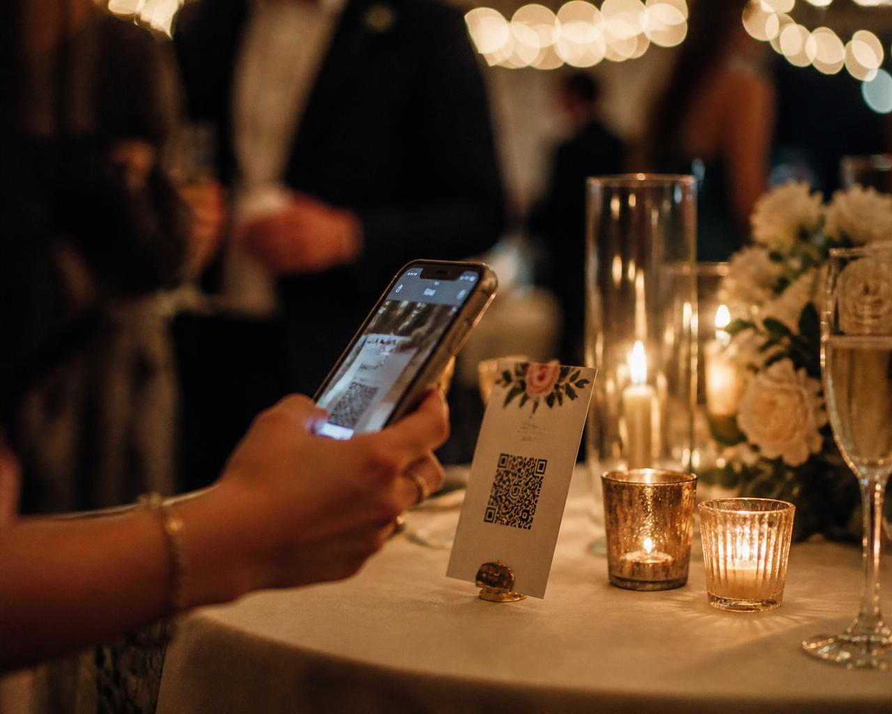 A guest scanning a printed table card with their phone at an evening event